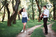 © soleg - young couple walking in the forest and playing guitar, summer nature, bright sunlight, shadows and green leaves, romantic feelings