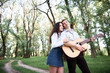 © soleg - young couple walking in the forest and playing guitar, summer nature, bright sunlight, shadows and green leaves, romantic feelings