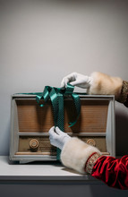 Crop Hand Of Santa Claus Touching Ribbon On Retro Radio