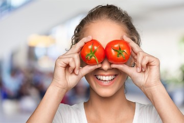 beautiful laughing woman holding two ripe tomatoes before her