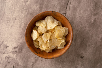 Potato chips on a bowl over wood background