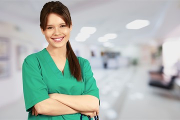 Wall Mural - Attractive young female doctor with blurred hospital interior on