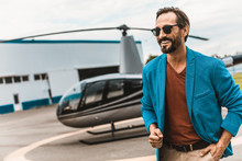 Cheerful Bearded Man In Stylish Colorful Clothes Smiling While Spending Time On The Helicopter Platform