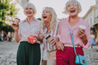 Waist up photo of stylish women holding cardboard glasses. White-haired females have fun together