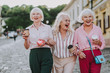 © Yakobchuk Olena - Waist up photo of three females with cardboard glasses in hands. White-haired old ladies alking together