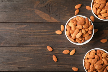 Sticker - Tasty organic almond nuts in bowls and space for text on table, top view