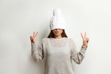 Sticker - Beautiful young woman in warm sweater with hat on white background