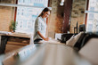© Yakobchuk Olena - Side view portrait of charming girl in blue shirt making notes while standing near table with printer