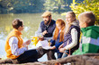 © zinkevych - Diligent pupil. Cute delighted boy looking at his teacher while sitting with him near the lake