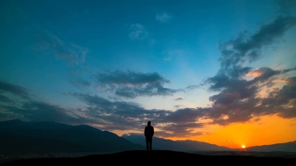 Wall Mural - The man standing on a mountain against a sunset with northern light. time lapse