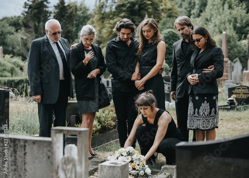 Fotomural Family laying flowers on the grave