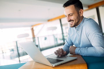 smiling male blogger keyboarding article in electronic newspaper using laptop