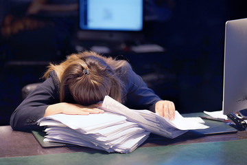 close-up of office worker is distressed with a lot of paperwork in front of her. a lot of paper work