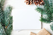 Merry Christmas and happy New year. Mockup with postcard and branches of a Christmas tree on white background. Background with copy space. Top view. Christmas background. Horizontal.