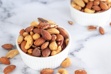 Sticker - roasted mixed nuts in white ceramic bowl on barble table background.