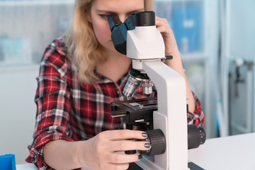 Wall Mural - Young woman medical researcher looking through microscop on slide