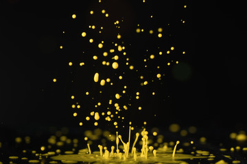 yellow paint, ink splash on black background