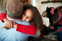 Granddaughter Giving Grandfather Hug As Multi Generation Family Celebrate Christmas At Home