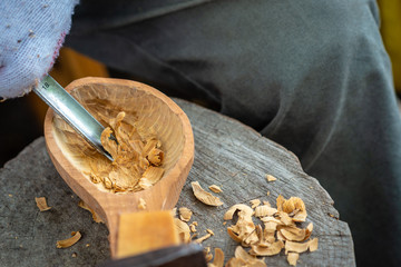 Wall Mural - Craftsman demonstrates the process of making wooden spoons handmade using tools. National crafts concept.