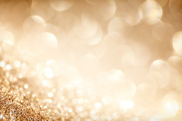 Golden sparkle glitters with bokeh effect and selectieve focus. Festive background with bright gold lights, champagne bubble. Christmas mood concept. Copy space, close up, texture, top view.