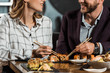 Partial view of smiling couple eating sushi in restaurant