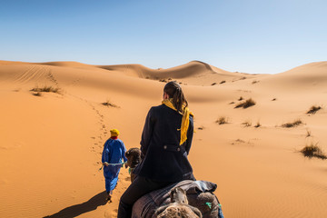 Wall Mural - berber nomad and a young girl riding camel in sahara desert, morocco