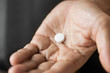 medicine, healthcare and people concept - close up of senior man hand with pill