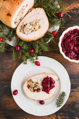 Wall Mural - Stuffed  turkey breast roll with cranberry sauce on white plate on rustic wooden table, top view