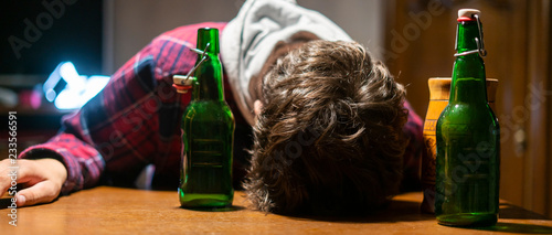 Fotomural young drunk man with glass and bottle of alcohol lying on the table f