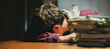 © Mihail - tired teenage pupil lying on the table doing homework late in the night f