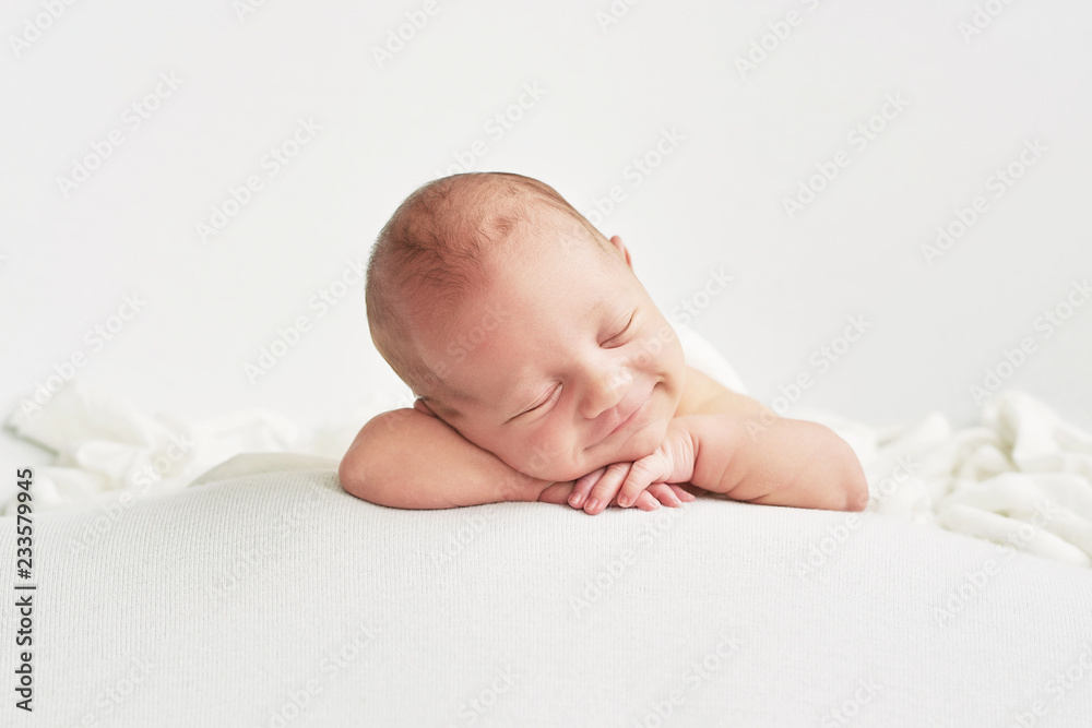 Cute newborn baby lies swaddled in a white blanket. Baby goods packaging template. Closeup portrait of newborn baby with smile on face. Healthy and medical concept.  - obrazy, fototapety, plakaty 