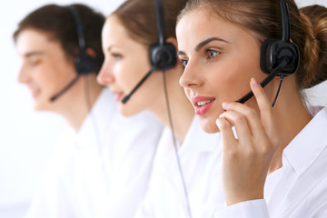 Wall Mural - Call center operators at work. Focus at beautiful business woman in headset