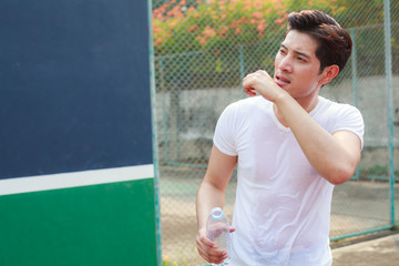 exhausted sweaty athletic man holding clean bottle of fresh mineral  drinking water outdoor under summer heat. Health care, Well being, Thirst Refreshment, Water Balance in body is medicine concept