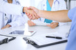 © rogerphoto - Two doctors shaking hands to each other at meeting. Teamwork and agreement in medicine