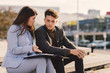 © Goran - Two young business colleagues sitting on staircase and discussing.