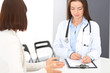 © rogerphoto - Doctor and  patient  discussing something while standing near reception desk in emergency hospital. Physician at work in clinic. Medicine and health care concept