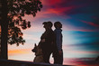 © Alexander - silhouettes of a couple with dog standing back on back at sunset