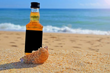 Little Bottle Whiskey In The Ocean Shells Stand On The Sand. Alcoholic Party In A Nautical Style On The Shores Of The Atlantic Ocean.