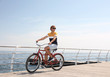 © New Africa - Attractive man riding bike near sea on sunny day