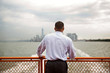 © Cavan for Adobe - Rear view of man standing at railing on ferry against cloudy sky