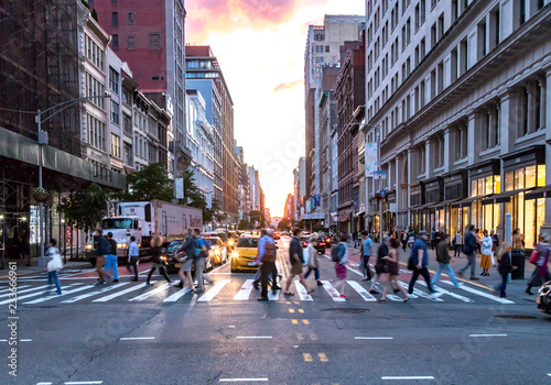 Plakat MIASTO NOWY JORK, CZERWIEC, 2018: Tłumy różnorodnych ludzi krzyżują ruchliwe skrzyżowanie przy 23 ulicy i 5th Avenue na Manhattanie z ruchem w godzinach szczytu w tle.