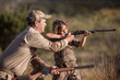 © Cavan for Adobe - Girl aiming with rifle while man assisting her on grassy field