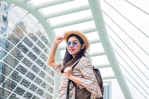 Foto Asian woman tourist with backpack wear hat standing smiling during a travel and relax in holiday in a landmark and attractions of Bangkok Thailand