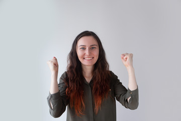 Positive pretty Caucasian girl clenching fists as symbol of victory. Young female spectator cheering favorite team. Fan support concept