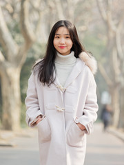 Portrait of beautiful young brunette woman in white winter fluffy coat. Outdoor fashion glamour Chinese teenage stylish lady. Emotions, people, beauty and lifestyle concept.