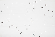 Holiday Backdrop Made Of Silver Stars And Sparkles On White Wooden Background. New Year Concept.