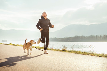 Wall Mural - morning jogging with pet: man runs together with his beagle dog