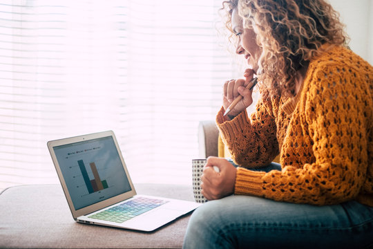 Young woman at home work with technology internet connected laptop sit down on the sofa for alternative freelance digital nomad office concept - enjoy lifestyle and business in modern way