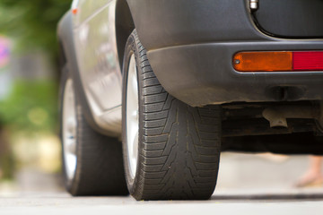 Detail of car, wheels with aluminum discs and new black rubber tire protector on light blurred background. Transportation, safety, reliability, modern design concept.