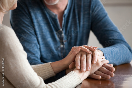 Fotomural Close up of sensual aged husband and wife holding hands enjoying romantic moment at home, caring senior couple caress and comfort each other, having tender sincere talk